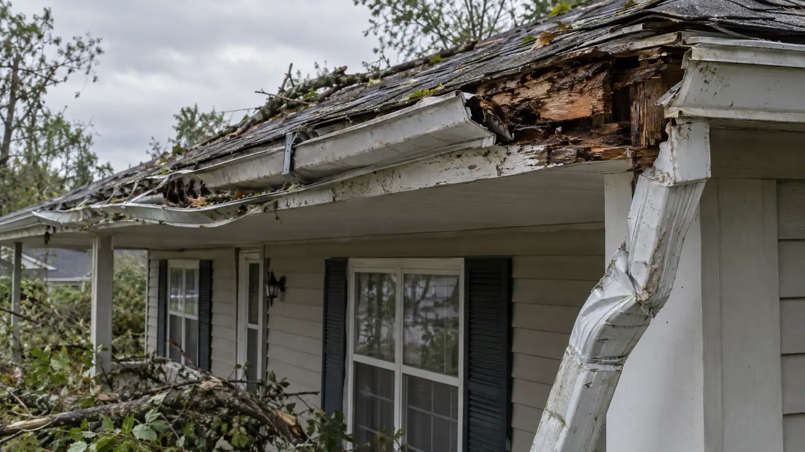 Before: a gutter ripped partly away from rotted fascia with a bent downspout